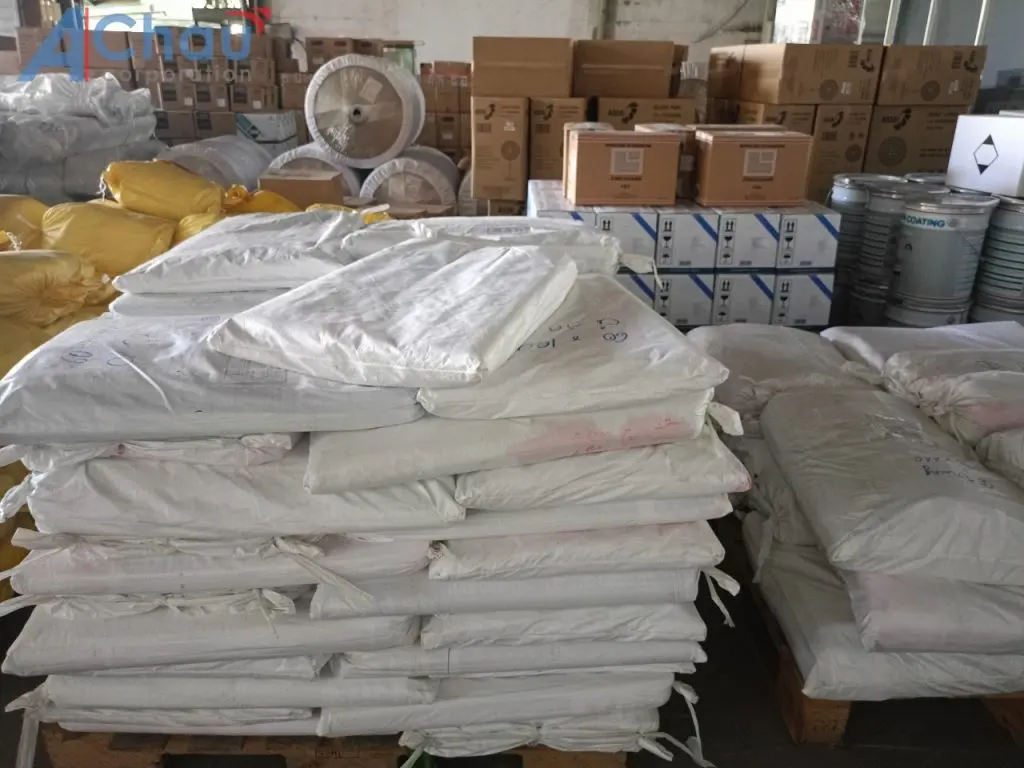 Bao hàng dệt xếp trên pallet cạnh thùng carton và lon sơn công nghiệp trong kho Á Châu