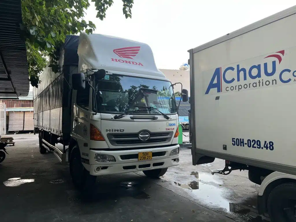 Xe tải Hino chụp chính diện tại bãi xe Á Châu, buồng lái hiện rõ kính lái và cửa hai bên