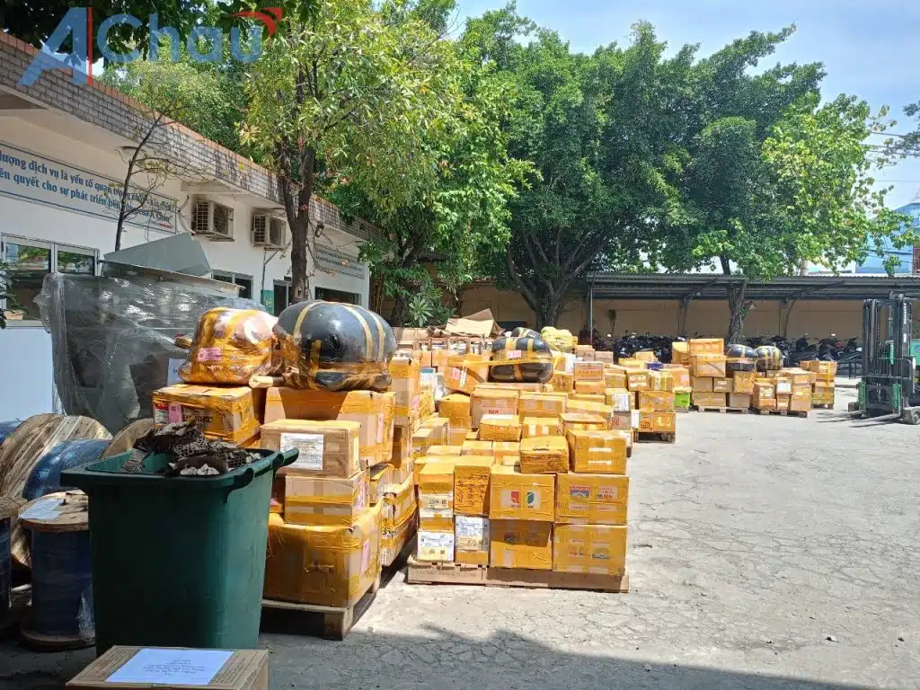 Bãi hàng lẻ tại kho Á Châu, các kiện bọc bao và thùng carton dán nhãn vận đơn xếp thành hàng chờ ghép chuyến