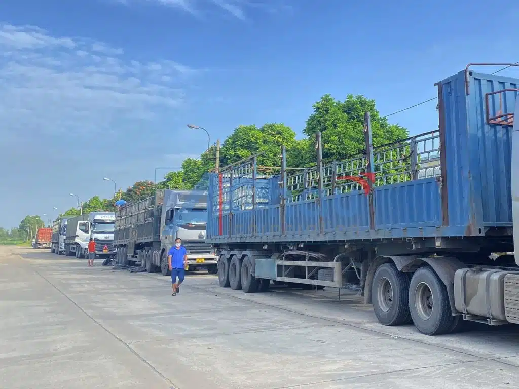 Xe tải và đầu kéo của Vận Chuyển Á Châu dừng bên lề đường, phía trước có tam giác cảnh báo phản quang đặt trên mặt đường