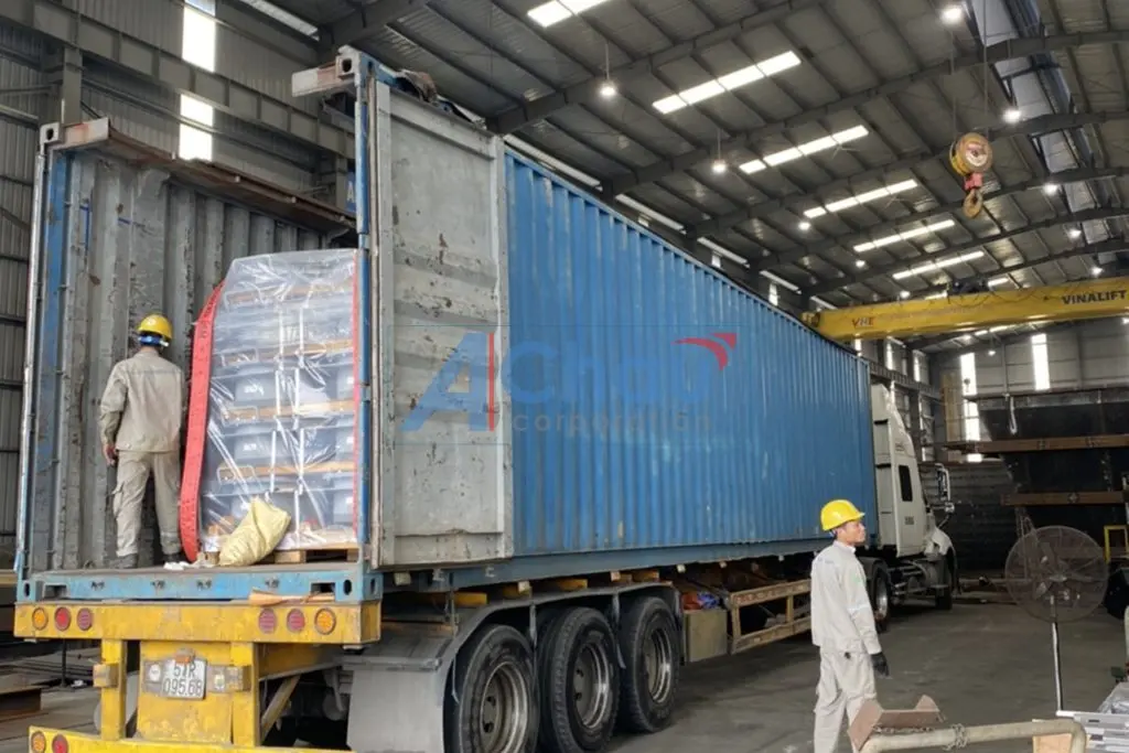 Công nhân Á Châu xếp pallet hàng công nghiệp vào container tại nhà xưởng khách hàng