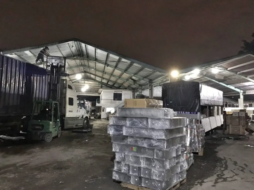 Hàng quấn màng PE xếp pallet và xe tải thùng bạt đang lên hàng trong kho Á Châu buổi tối, chuẩn bị chạy tuyến đi Quảng Trị