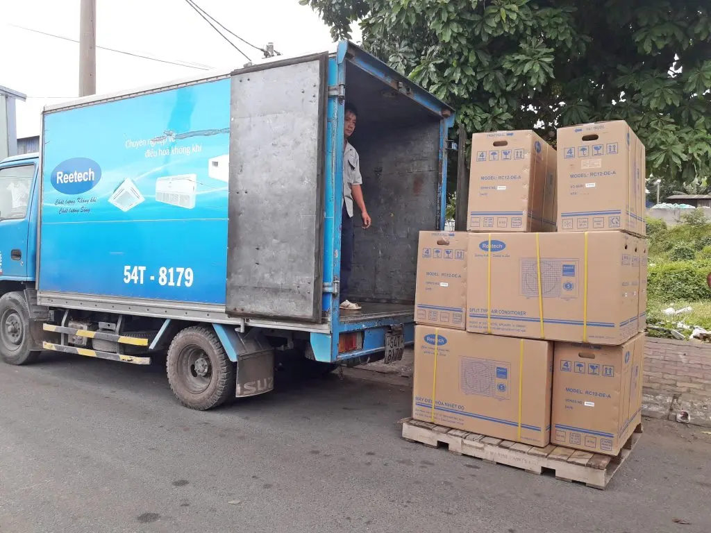 Nhân viên đứng trong thùng xe tải kín chuẩn bị nhận kiện hàng điện máy xếp sẵn trên pallet bên ngoài