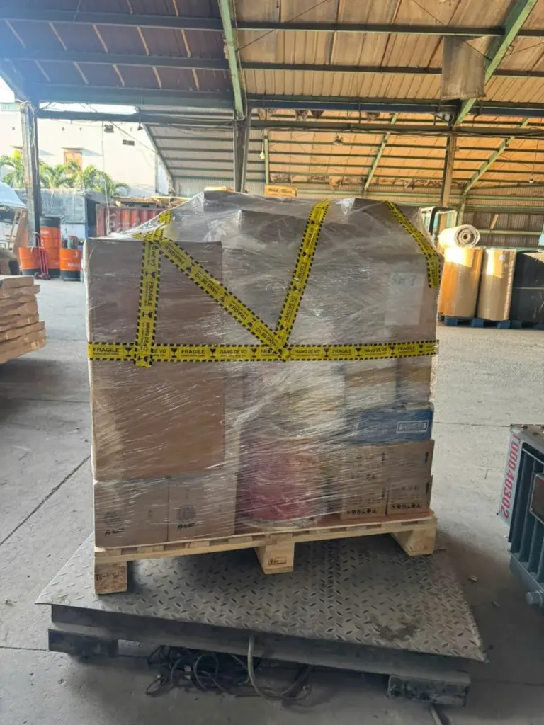Kiện hàng bọc màng dán băng dễ vỡ đặt trên cân sàn tại kho Á Châu