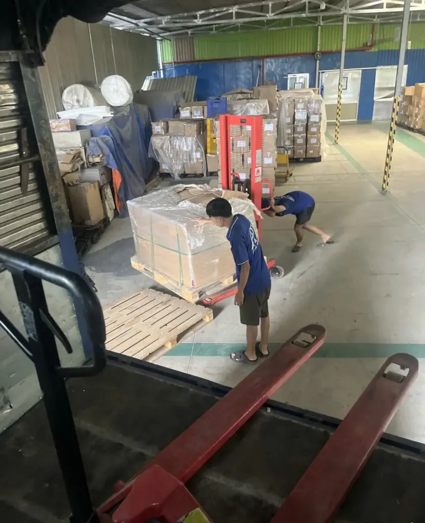 Nhân viên dùng xe nâng tay đẩy pallet hàng trong kho